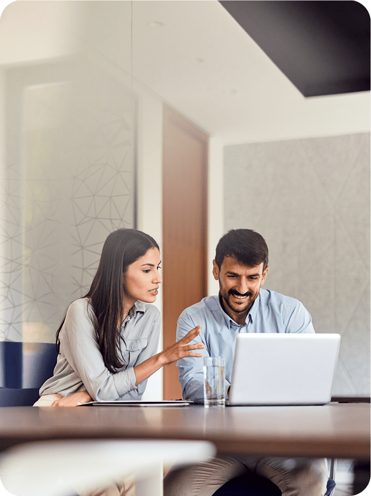 Two colleagues discussing work at a laptop in an office.